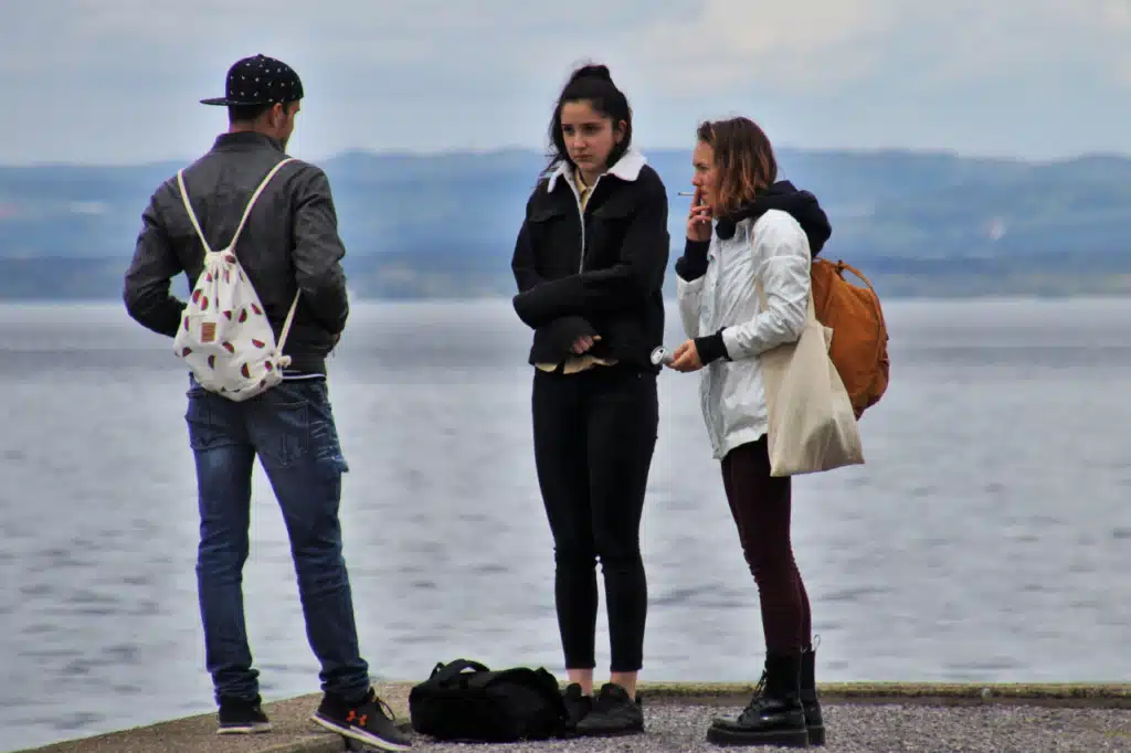 Den gode samtale - 2 kvinder og 1 mand snakker på strand. Den ene kvinder ryger en cigaret