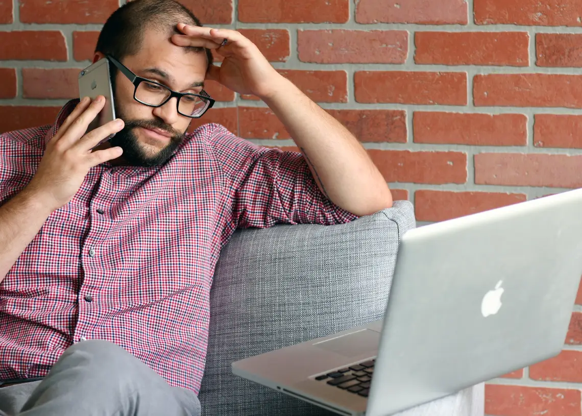 stress på arbejdspladsen - mand sidder med MacBook og ser stresset ud