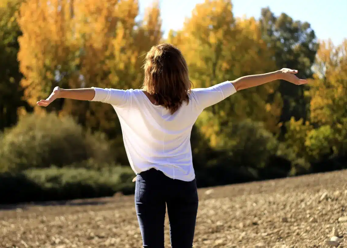 Hvad er motivation også - her en kvinde med armene i vejret i en skovlysning